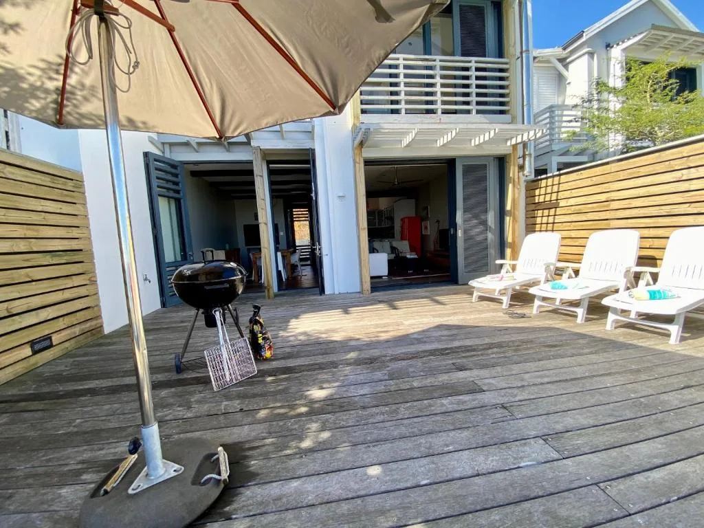 Spacious outdoor deck with lounge chairs, umbrella, and braai area
