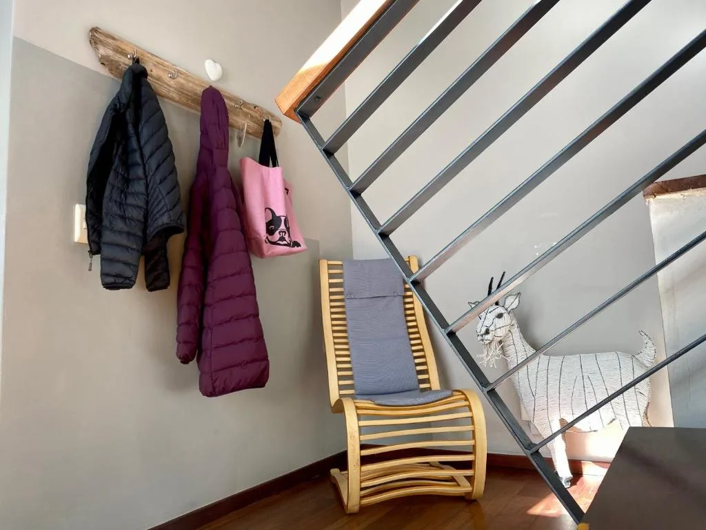 Rustic wooden coat rack with hanging jackets and winter clothing near stairs