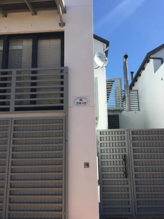 Modern white townhouse facade with black-trimmed windows and metal gates