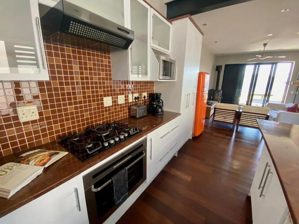 Modern kitchen with terracotta tile backsplash, gas cooktop, and wooden counters