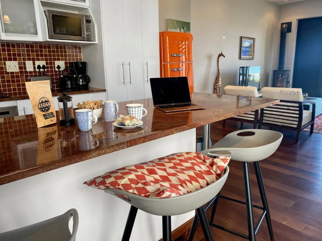 Modern kitchen with red tile backsplash, orange retro fridge, and island seating