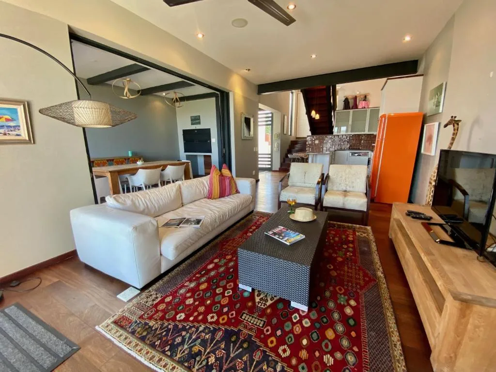 Open-plan lounge with cream sofa, patterned rugs, and TV entertainment area