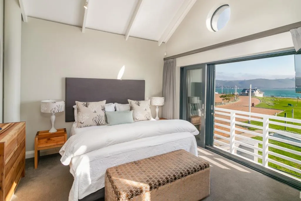 Bright bedroom with king bed, ocean and lagoon views through glass doors
