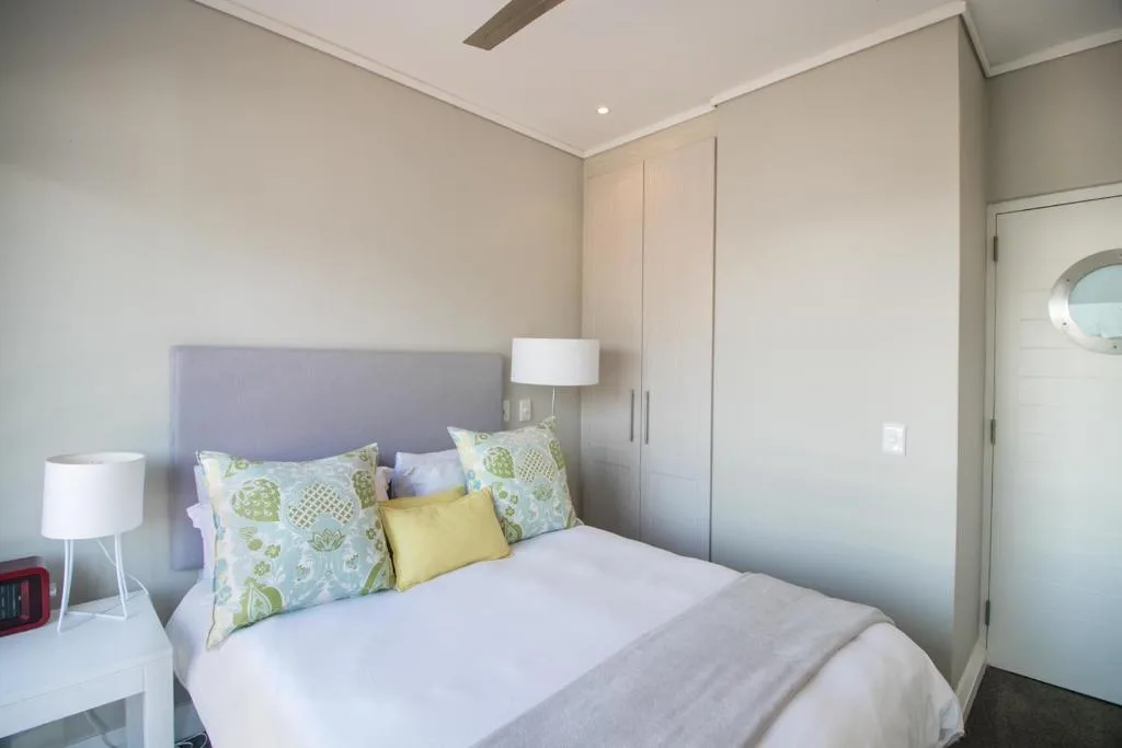Bright bedroom with queen bed, patterned pillows, and modern furnishings