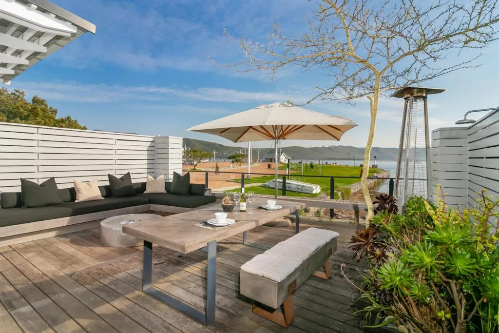 Spacious outdoor deck with seating, umbrella, and lagoon view