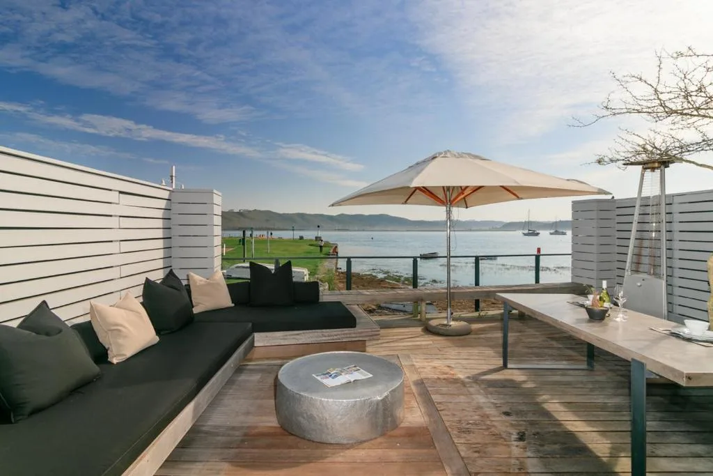 Waterfront deck with seating, umbrella, and lagoon views in Knysna