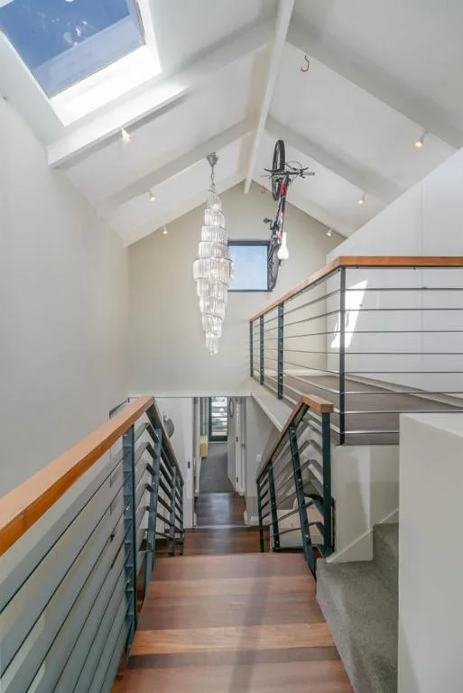 Modern staircase with wooden handrails and metal railings, skylights above