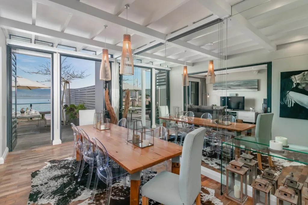Modern dining area with wooden table, ocean views through glass doors