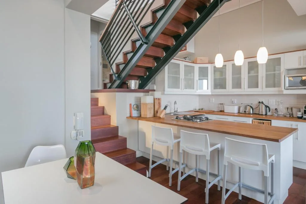 Modern kitchen with white cabinetry, wooden counters, and island seating