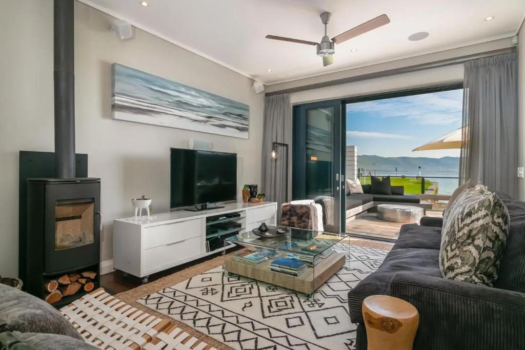 Modern living room with fireplace, TV, and ocean views through glass doors