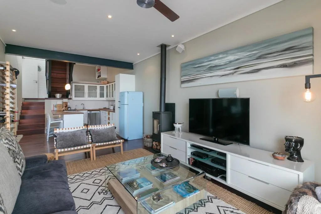 Modern lounge with TV, sofa, fireplace, and open-plan kitchen visible beyond