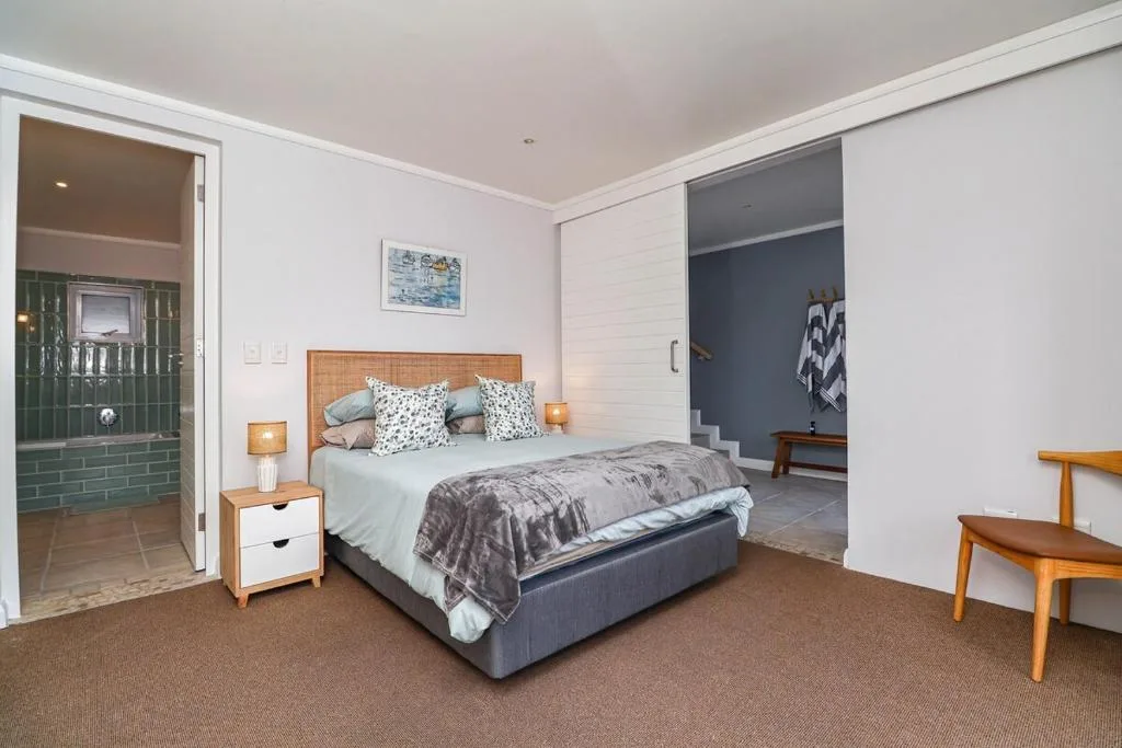 Spacious bedroom with queen bed, wooden headboard, and ensuite bathroom entrance