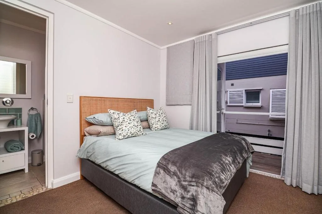 Bright bedroom with wooden headboard bed and patterned pillows