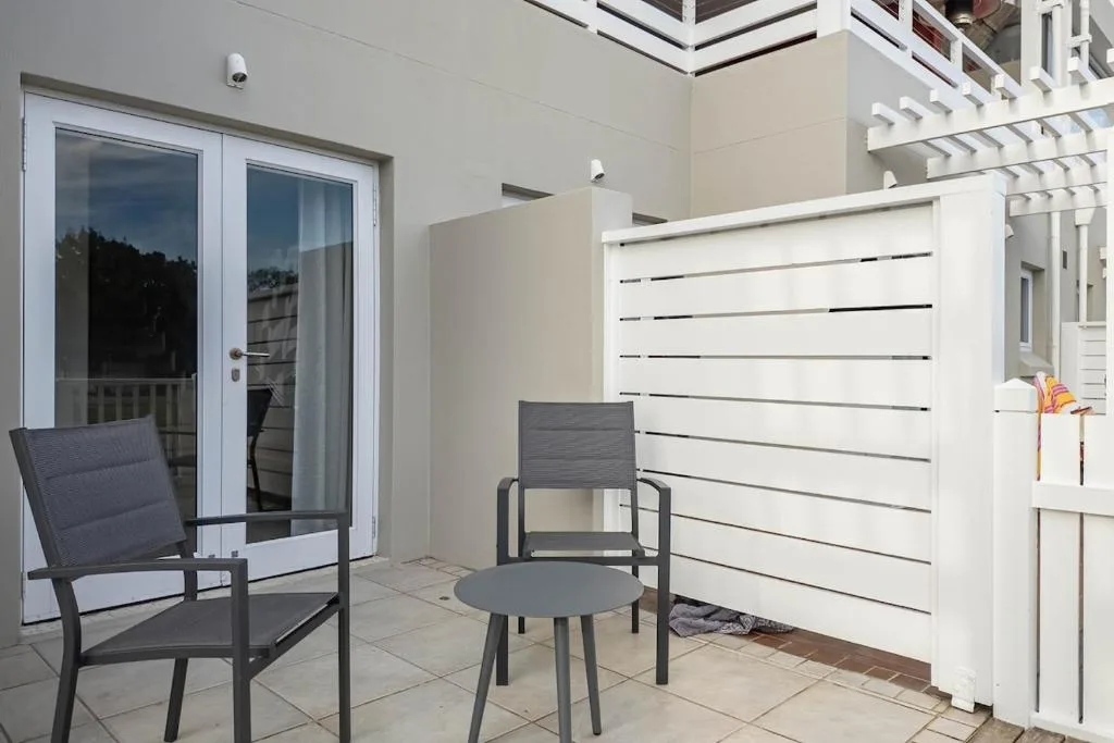 Modern patio with seating, white privacy screen, and glass doors
