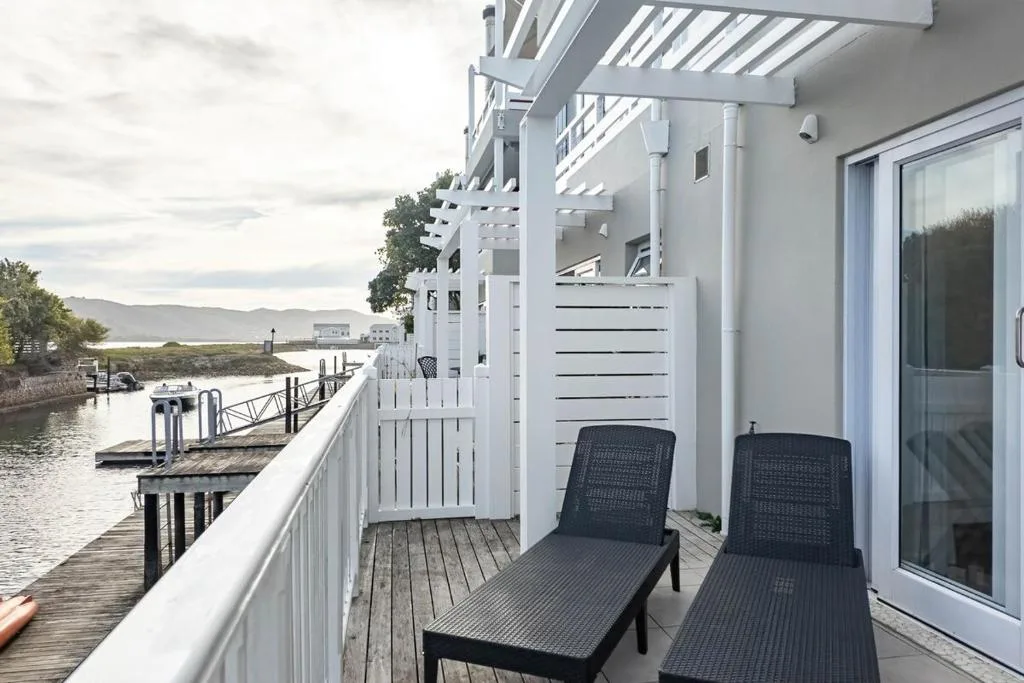 Waterfront deck with loungers, pergola, and lagoon views at Thesen Island