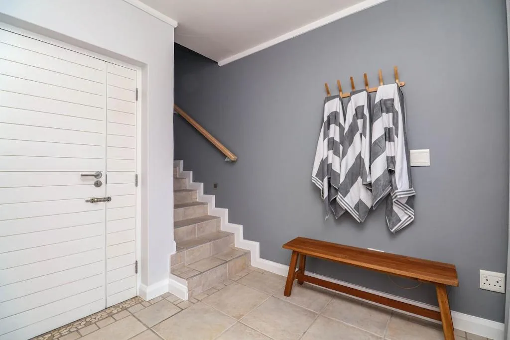 Entryway with wooden bench, towel rack, and white door leading inside