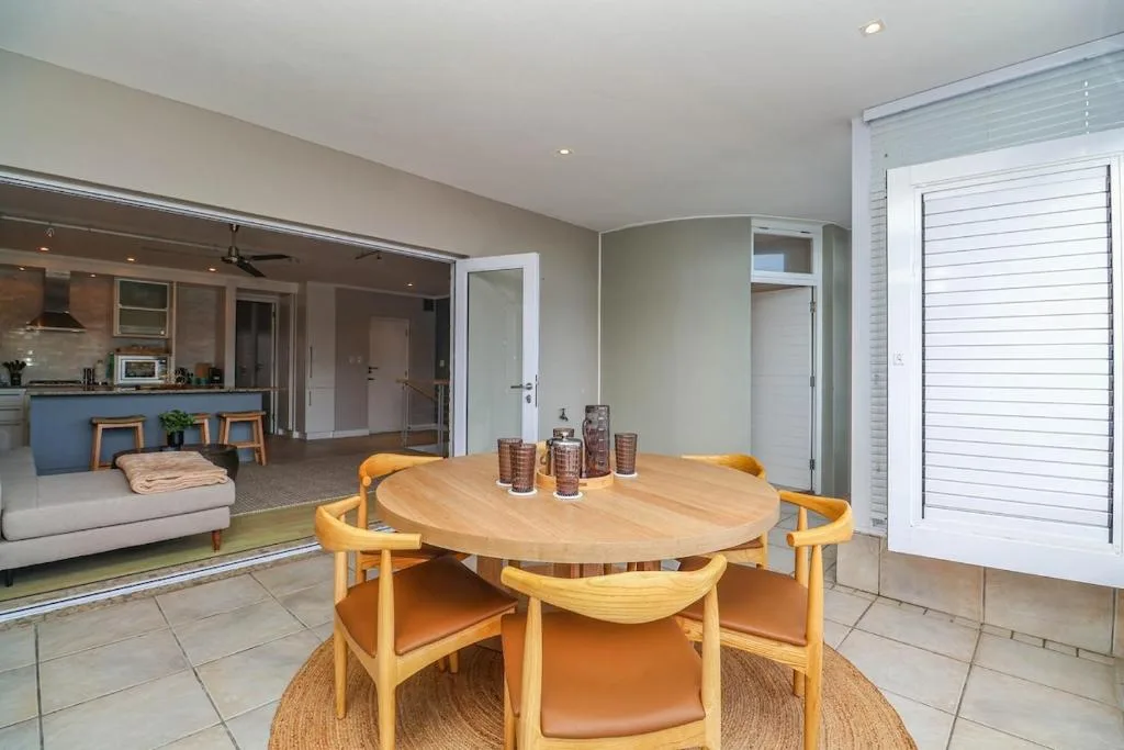 Modern dining area with round wooden table and orange chairs, open-plan layout