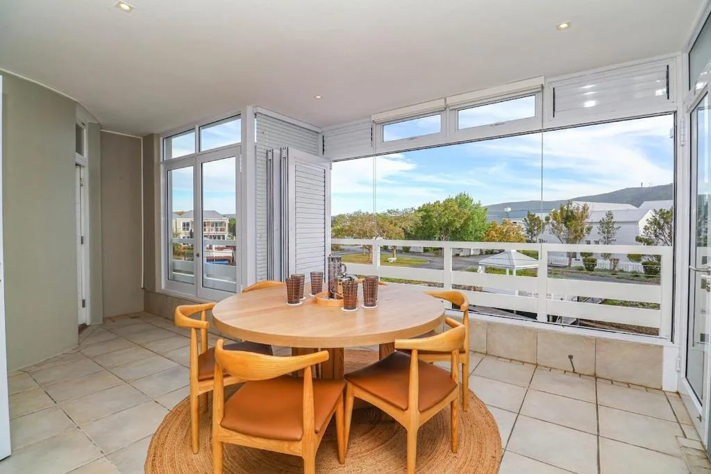 Bright dining area with round wooden table and chairs overlooking lagoon views
