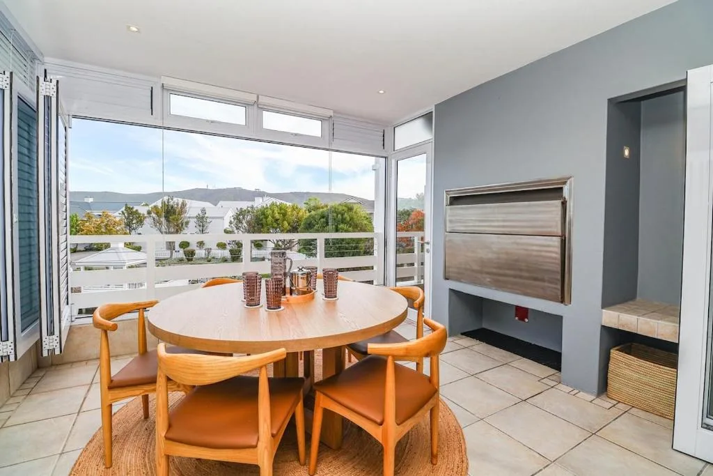 Round wooden dining table with orange chairs overlooking mountain views