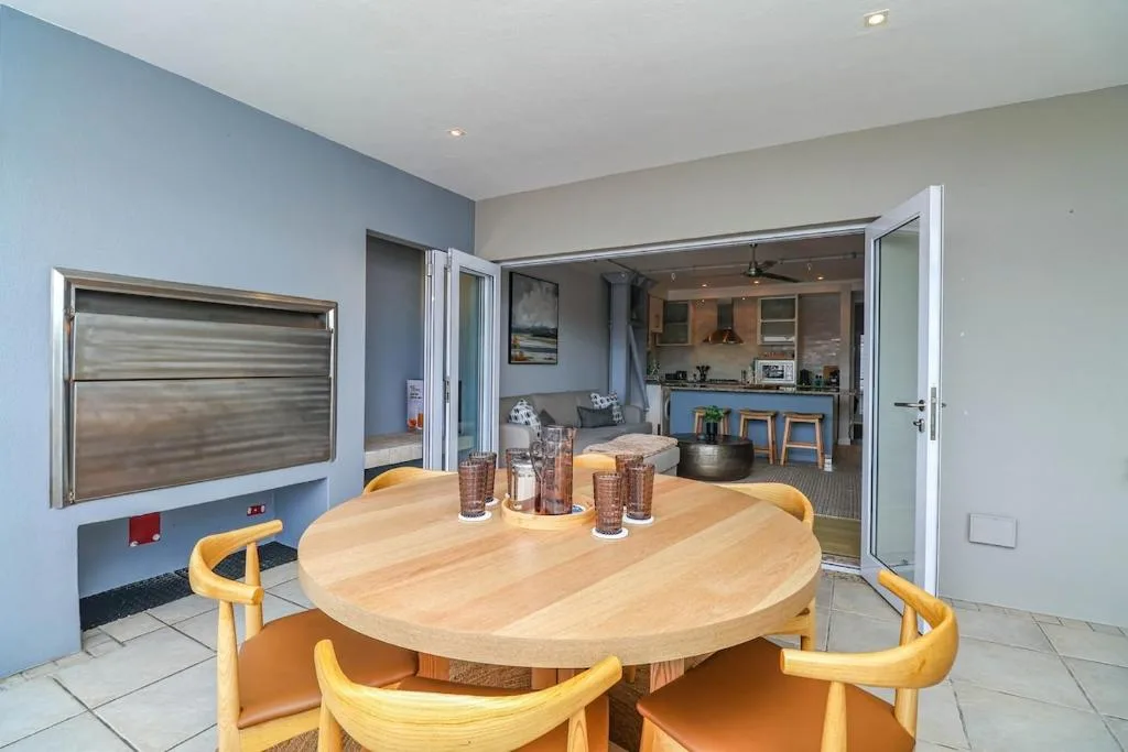 Modern dining area with wooden table and yellow chairs, open to kitchen