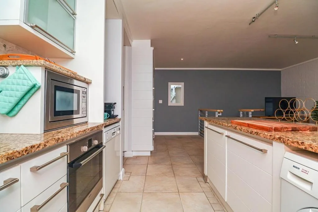 Modern kitchen with white cabinetry, granite countertops, stainless steel appliances