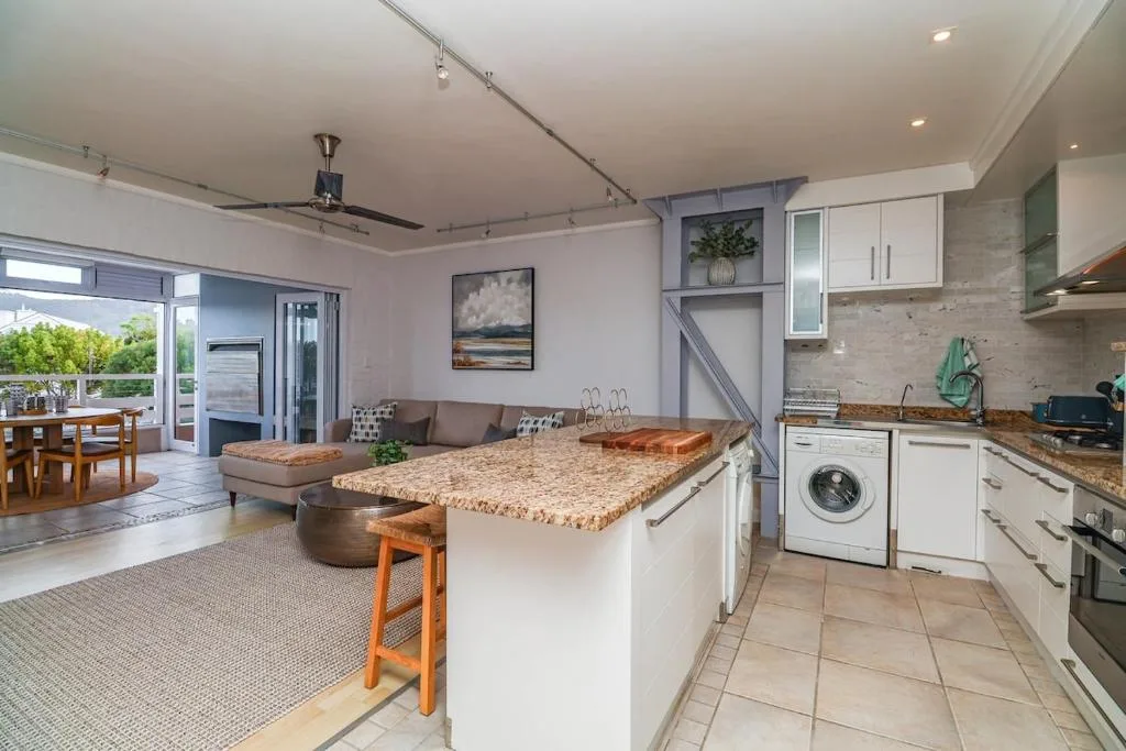 Modern kitchen with granite countertops, white cabinetry, and open plan living space