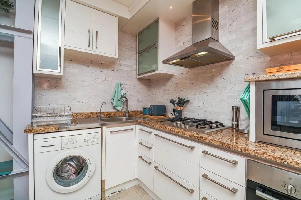 Modern kitchen with white cabinetry, granite countertops, gas stove, and stainless steel appliances