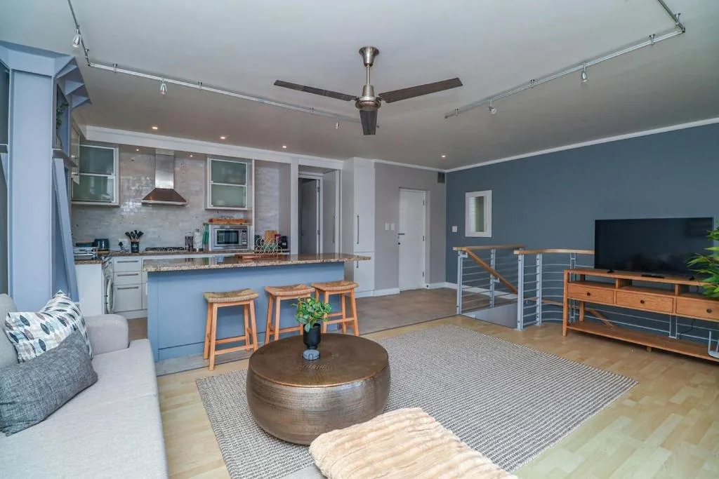 Open-plan living area with sofa, TV, and modern ceiling fan overhead