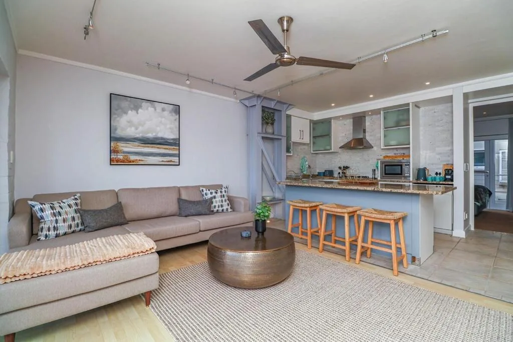 Modern living room with beige sofa, round bronze coffee table, and open kitchen