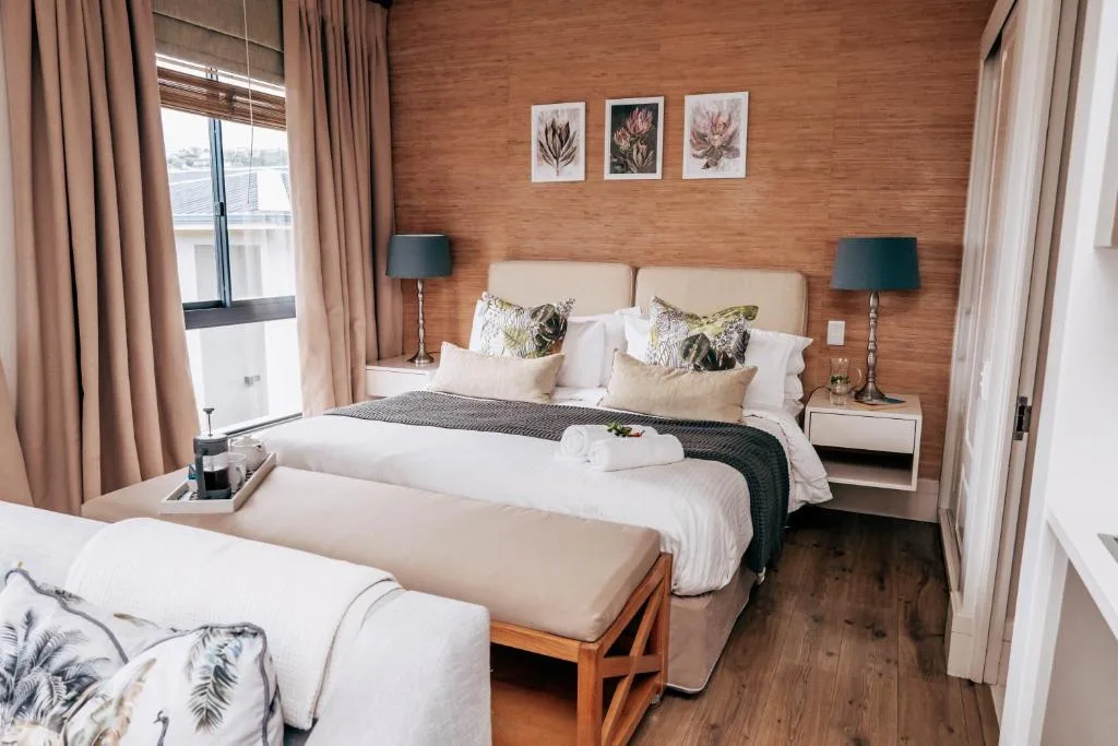 Modern bedroom with queen bed, warm wood accent wall, botanical artwork