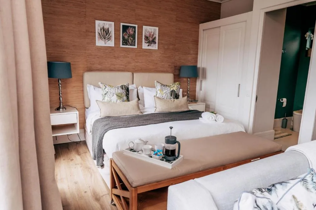Spacious bedroom with queen bed, wooden accent wall, and botanical artwork