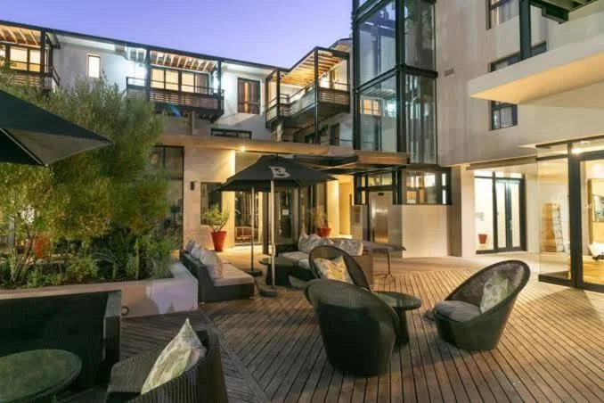 Spacious wooden deck with black wicker chairs and evening lighting