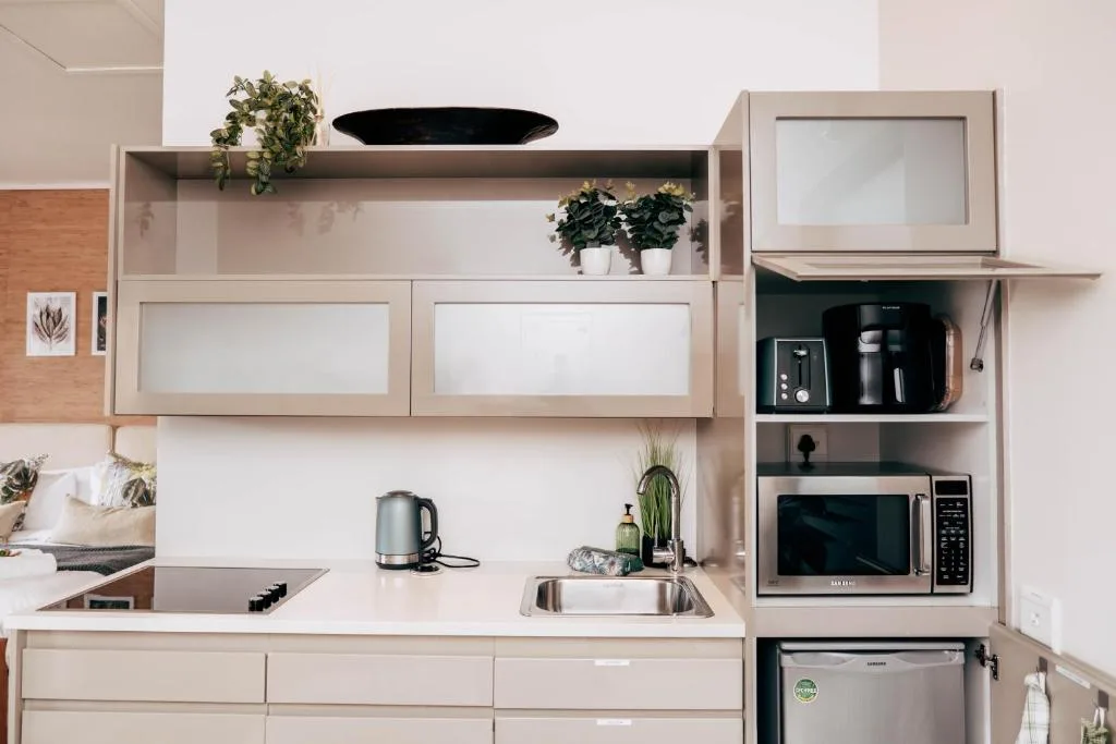Modern kitchen with sink, kettle, microwave, and open shelving with plants