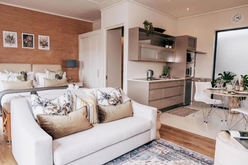 Modern lounge with white sofa, wooden accent wall, and integrated kitchenette