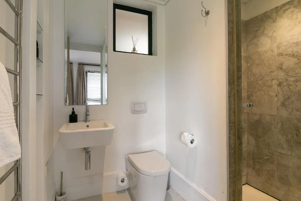 Modern bathroom with marble shower, vanity sink, and toilet fixtures