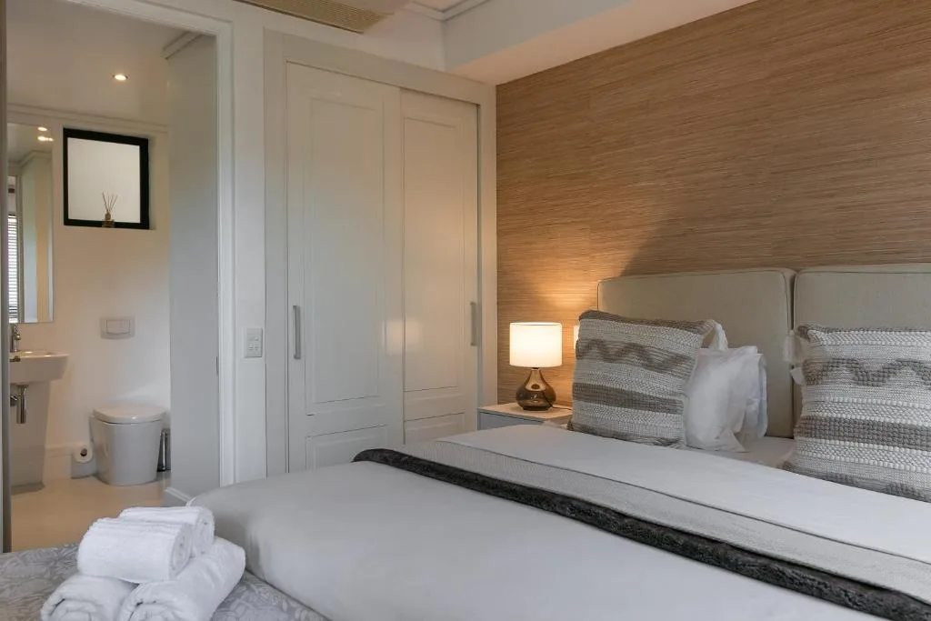 Modern bedroom with wooden accent wall, bed, and ensuite bathroom visible