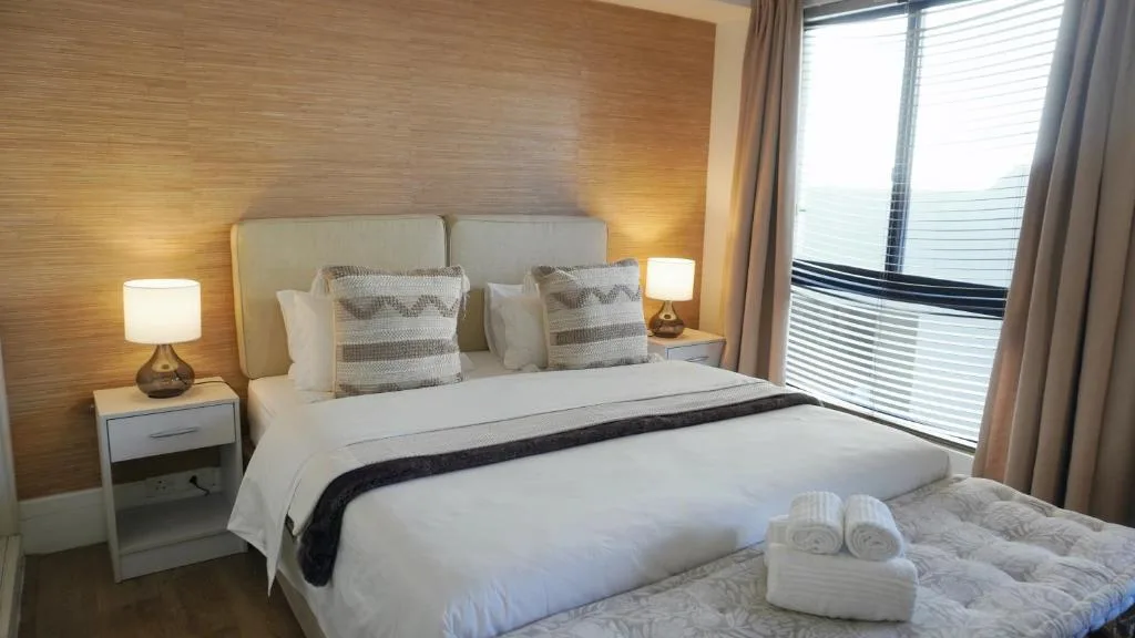 Modern bedroom with king bed, warm lighting, and ocean view windows