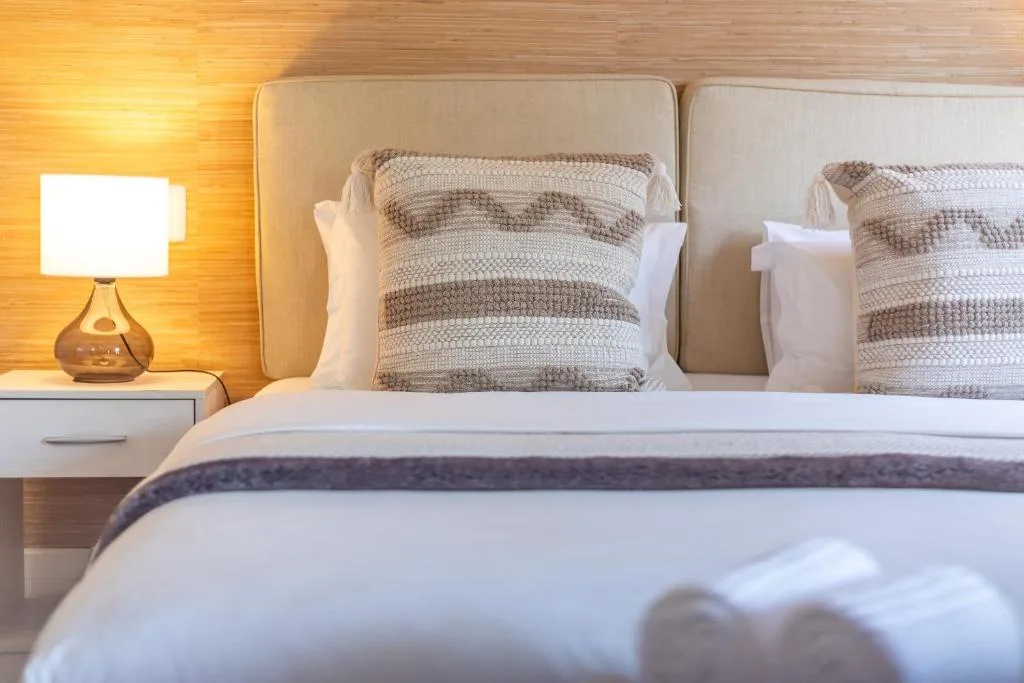Contemporary bedroom with twin beds, striped pillows, and warm bedside lighting