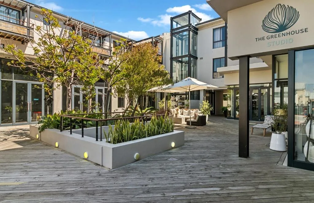 Modern courtyard patio with wooden decking, planters, and white umbrellas
