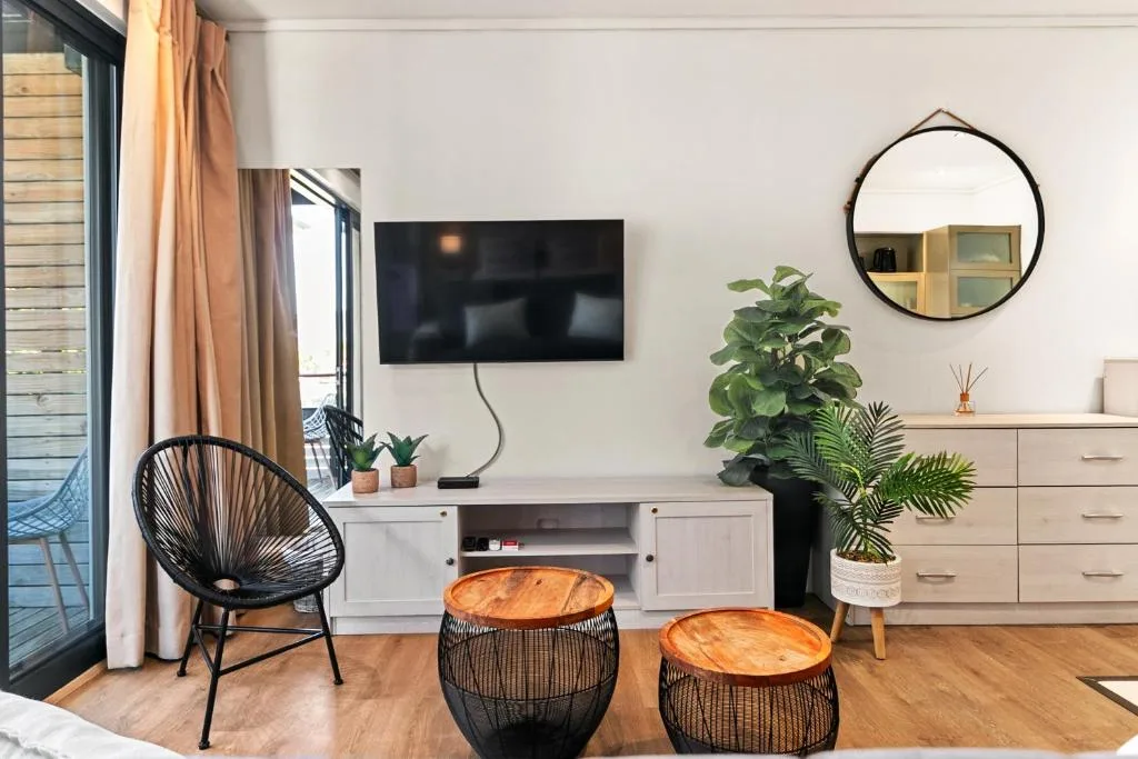 Modern lounge with TV, comfortable seating, plants, and deck access