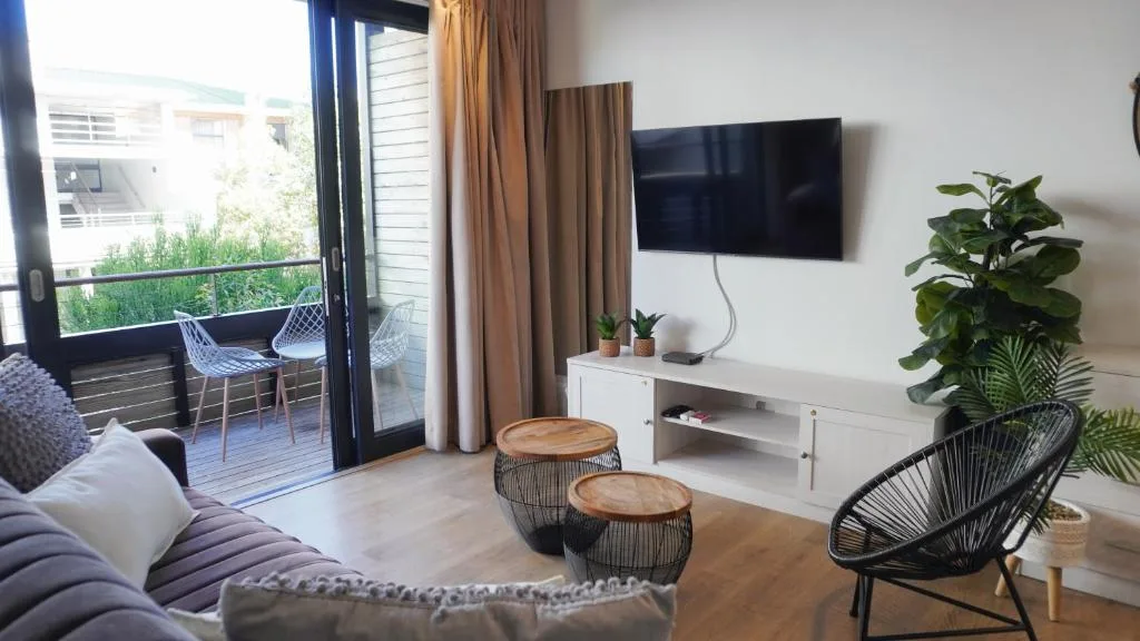 Modern lounge with sofa, wall-mounted TV, and access to deck area