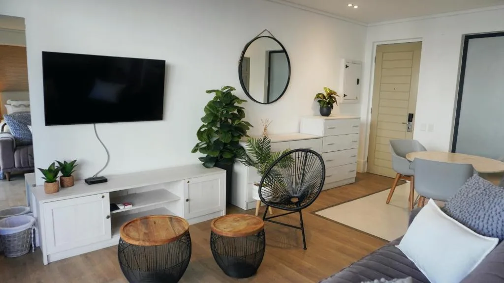 Modern lounge with wall-mounted TV, comfortable seating, and potted plants
