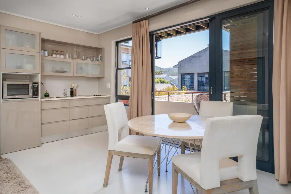Modern dining area with round table and cream chairs overlooking garden route
