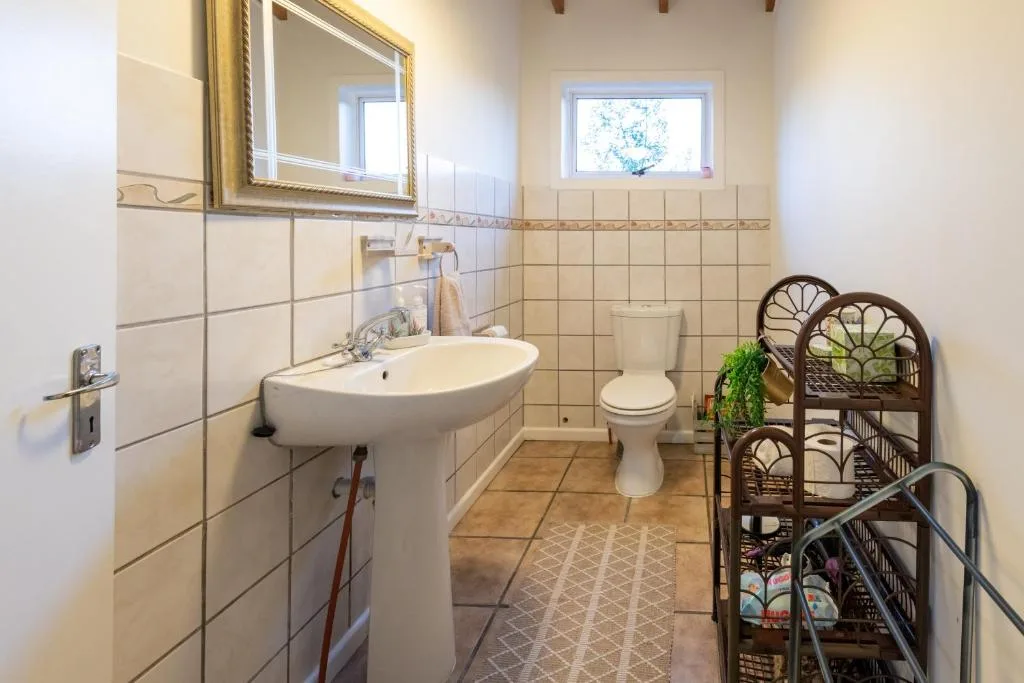 Bright bathroom with pedestal sink, toilet, and tiled walls