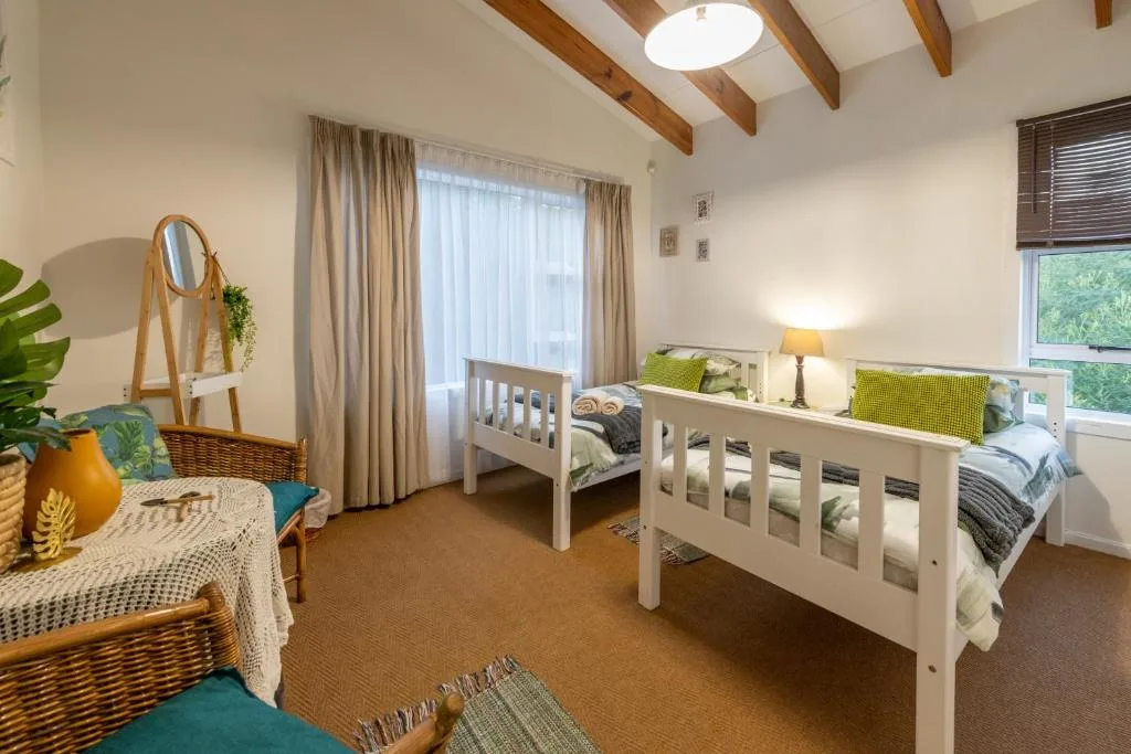Bright bedroom with two white beds and exposed wooden beams overhead