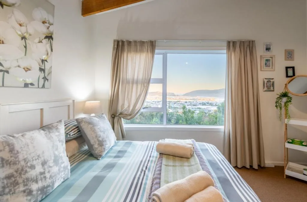 Bright bedroom with lagoon and mountain views through large windows