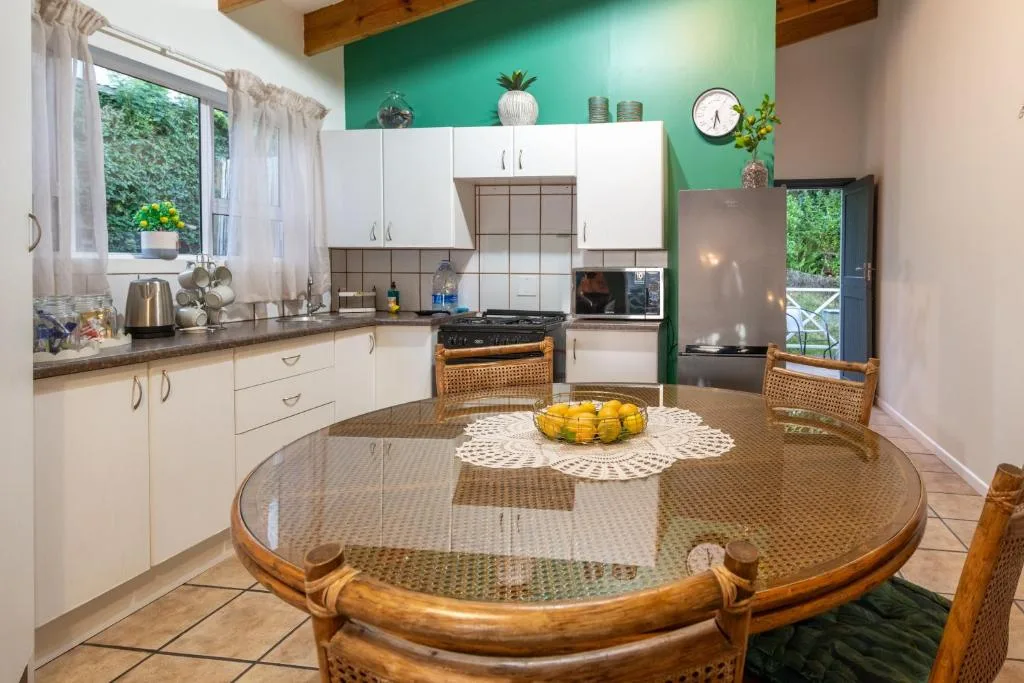 Modern kitchen with white cabinets, green accent wall, and round dining table