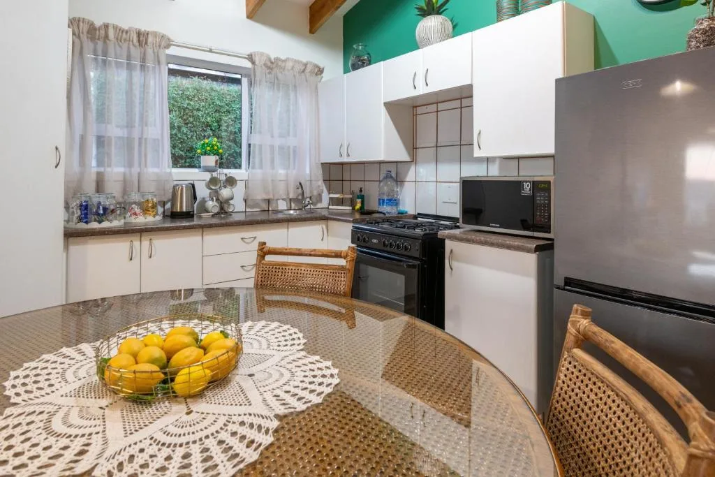 Modern kitchen with white cabinetry, black gas range, and round dining table with fresh lemons