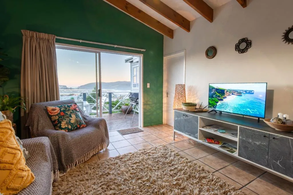 Spacious lounge with green accent wall, comfortable seating, and lagoon views through glass doors