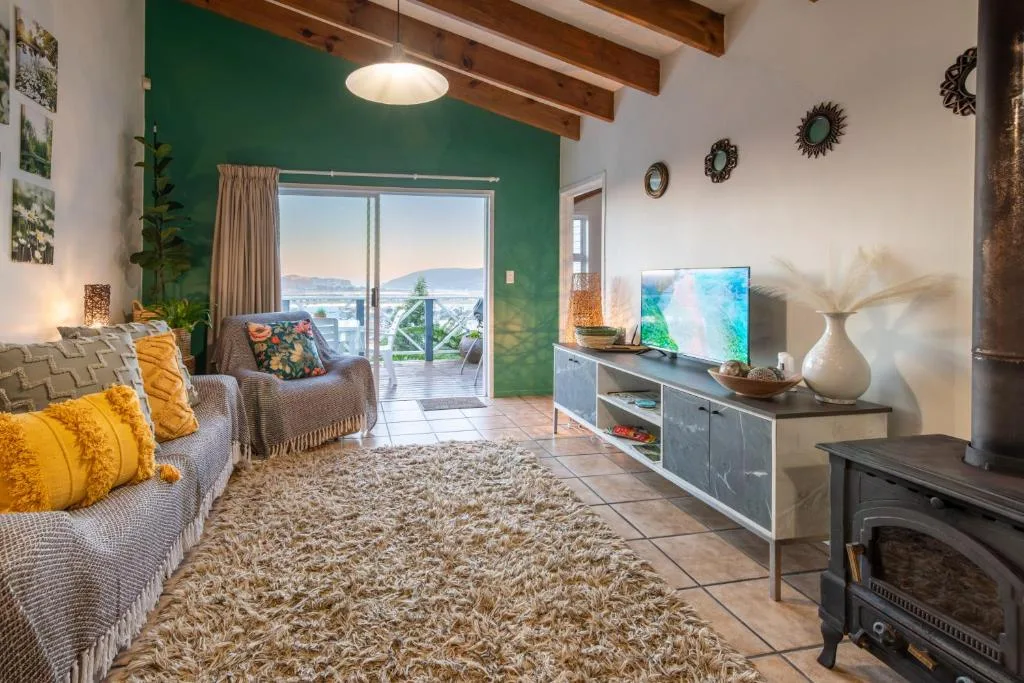 Spacious lounge with green accent wall, comfortable seating, and lagoon views through glass doors